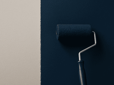 A paint roller applying a deep navy blue paint to a feature wall, next to a light grey wall.