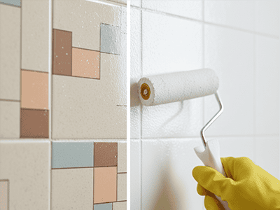 A small foam roller applying a specialised white tile paint over dated patterned tiles.